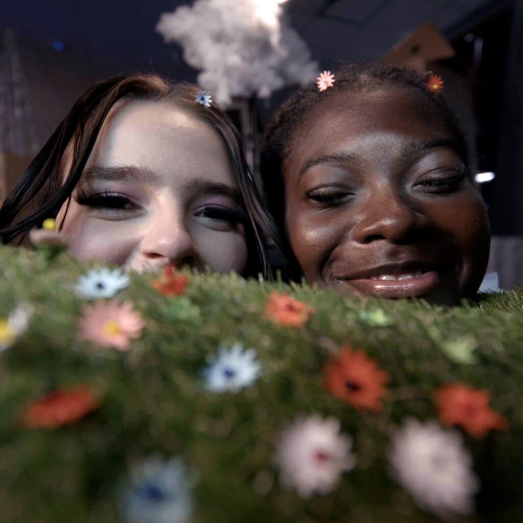 Two girls on a miniature grass field with flowers